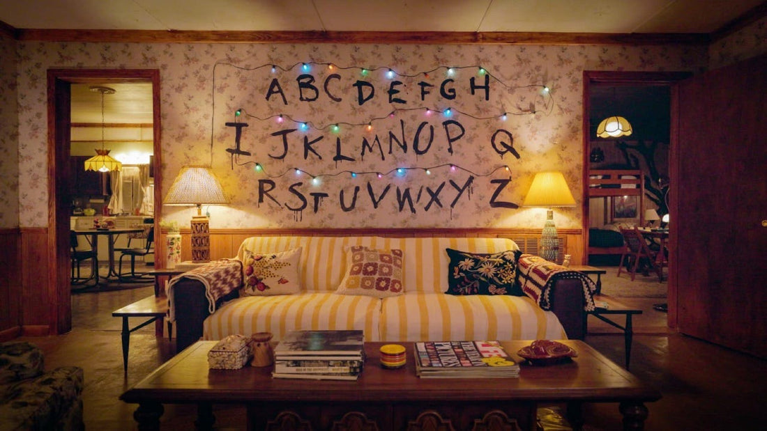 Das Wohnzimmer eines Hauses in Hawkins: Alphabetwand, leuchtende Lichterkette und gelbes 80er-Sofa