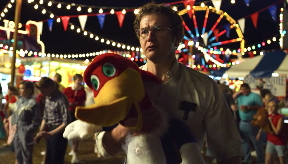 Alexei auf dem Jahrmarkt, ein Plüschvogel im Arm, das Riesenrad hinter ihm.