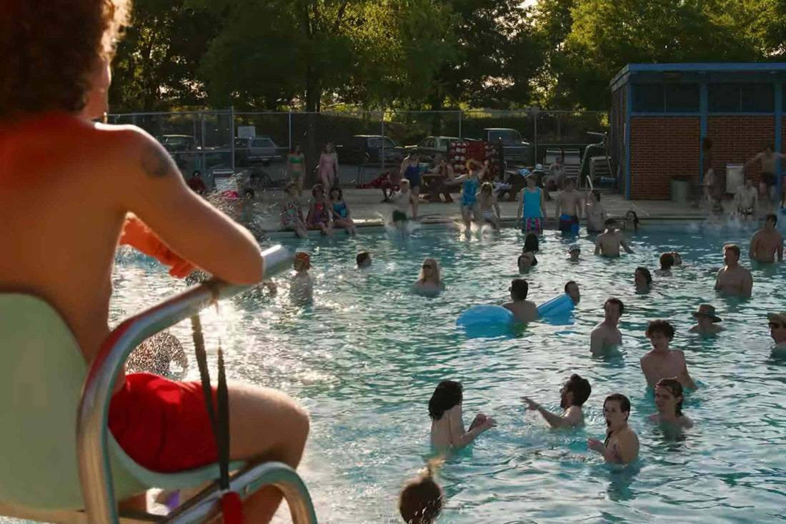 Voller städtischer Pool im Sommer, der Rettungsschwimmerstuhl im Vordergrund.
