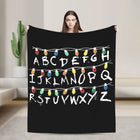 Kuscheldecke Stranger Things Buchstaben und Glühbirnen weiß