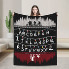Kuscheldecke Stranger Things Alphabet vor Waldhintergrund